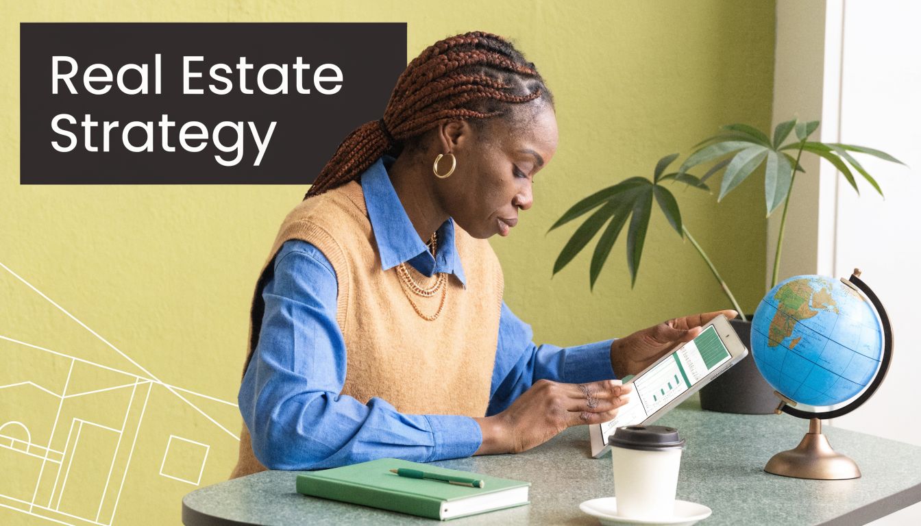 A professional woman in a sweater vest analyzes real estate data on a tablet at her desk.