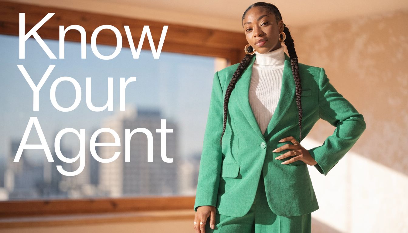 A professional real estate agent wearing a green suit standing in front of a window.